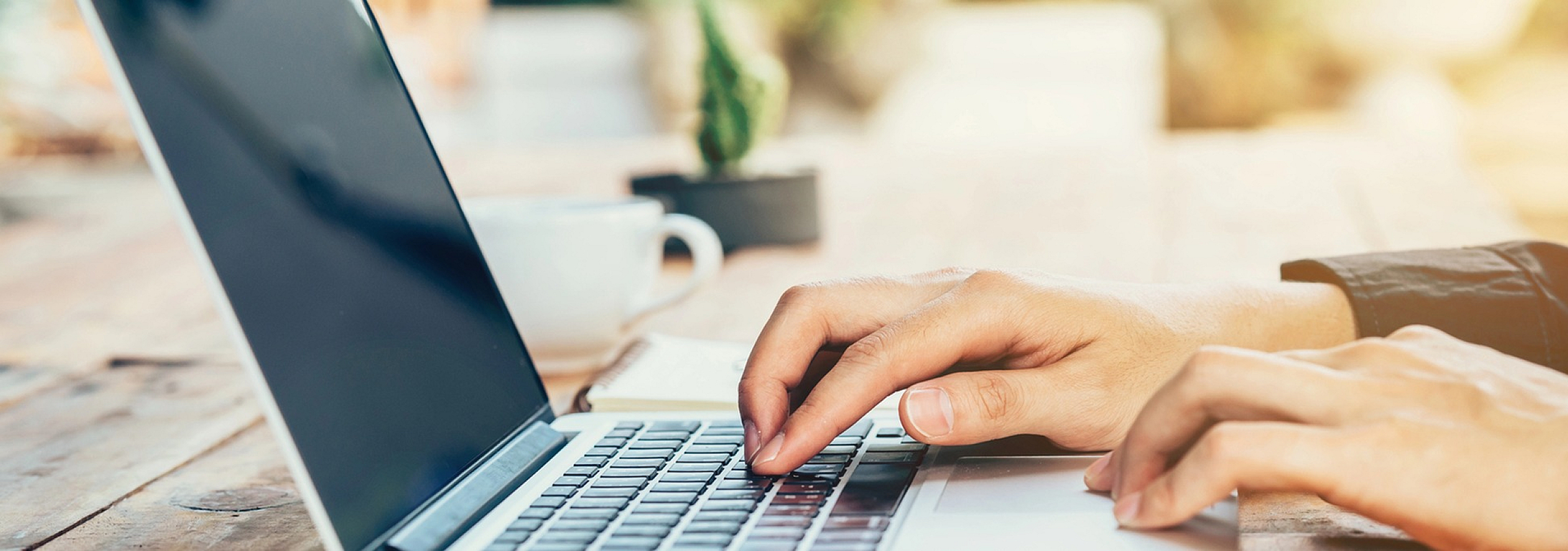 Serene outdoor workspace showcasing hands typing on a sleek laptop amidst lush greenery, ideal for productive remote work.