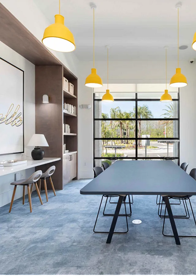 Sleek modern meeting room with large windows, stylish wooden bookshelves, and vibrant yellow pendant lights.