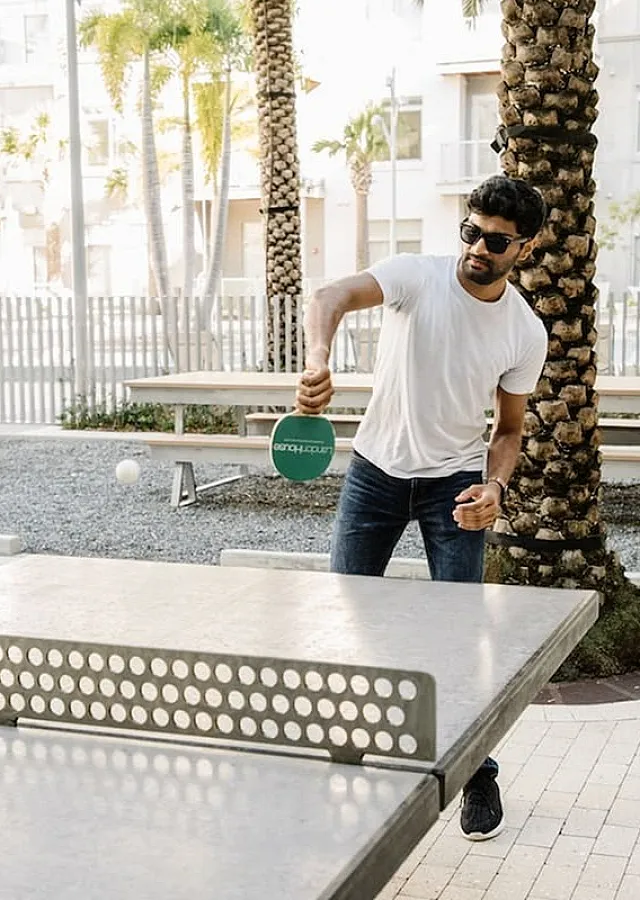 Vibrant outdoor ping pong area with a modern design, surrounded by palm trees, offering a fun and engaging community space.
