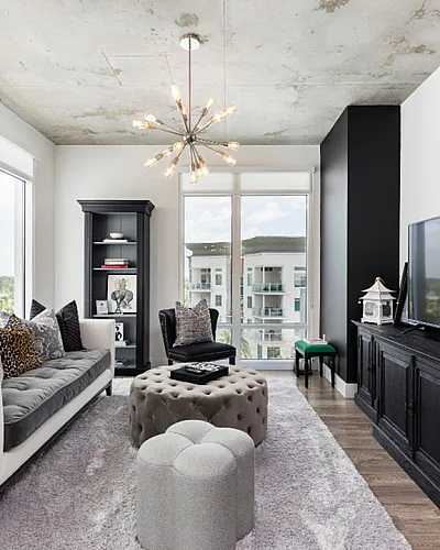 Chic modern living room with large windows offering bright natural light, featuring stylish furniture, a sleek entertainment center, and contemporary decor.