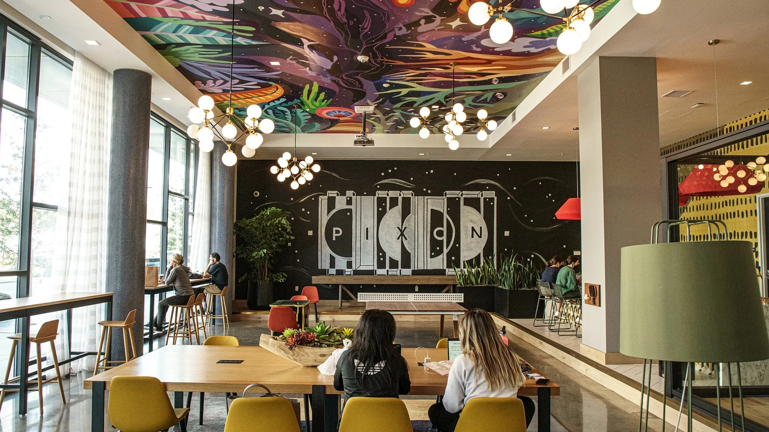 Vibrant and modern community space with artistic ceiling, stylish lighting, and comfortable seating, perfect for social gatherings or study sessions.