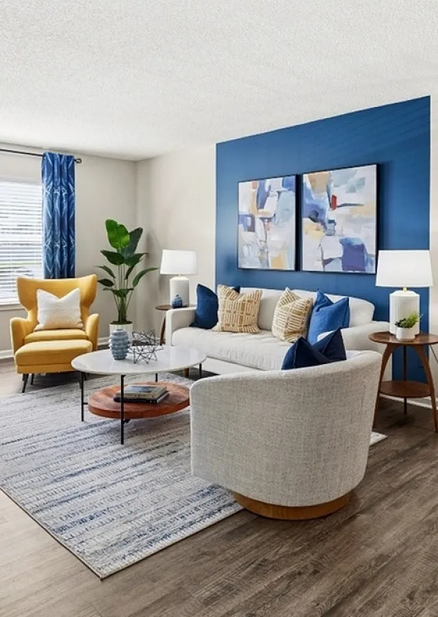 Modern living room featuring elegant decor with a cozy sofa, vibrant blue accent wall, and natural light through large window.