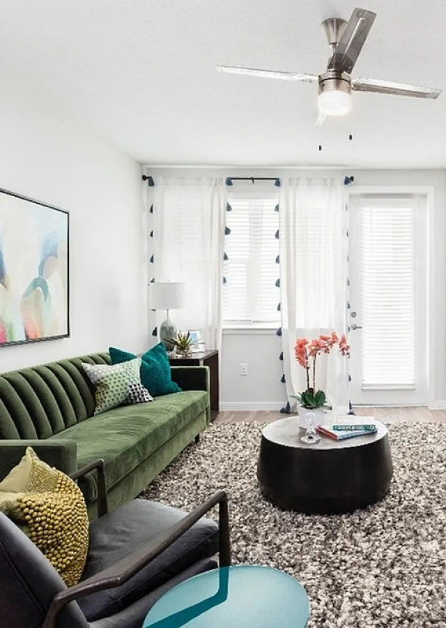 Chic and airy living room with a plush green sofa, modern art, and bright natural light flowing through sheer curtains.