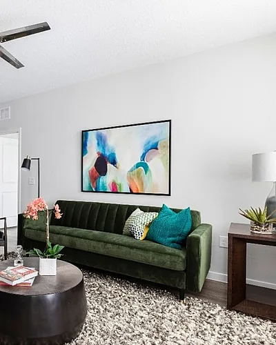 Modern open-plan living space with a chic kitchen, cozy green sofa, and vibrant artwork creating an inviting atmosphere.