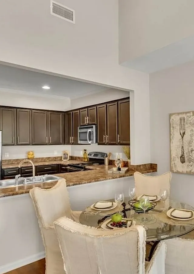 Elegant open kitchen and dining area with modern appliances, rich dark cabinetry, and a cozy dining table setting for four.