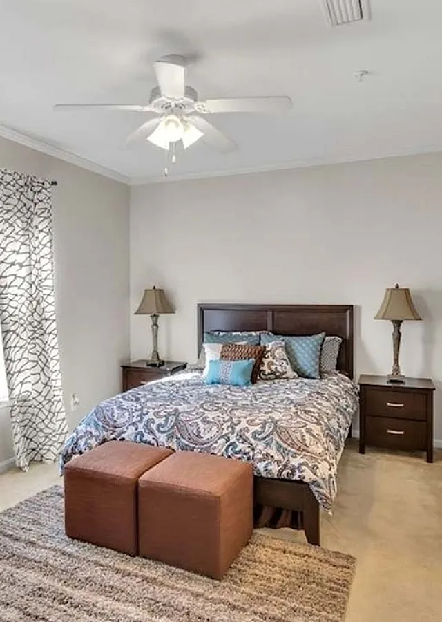 Inviting bedroom with elegant decor, featuring a cozy bed, patterned curtains, and soft carpeting for ultimate comfort.