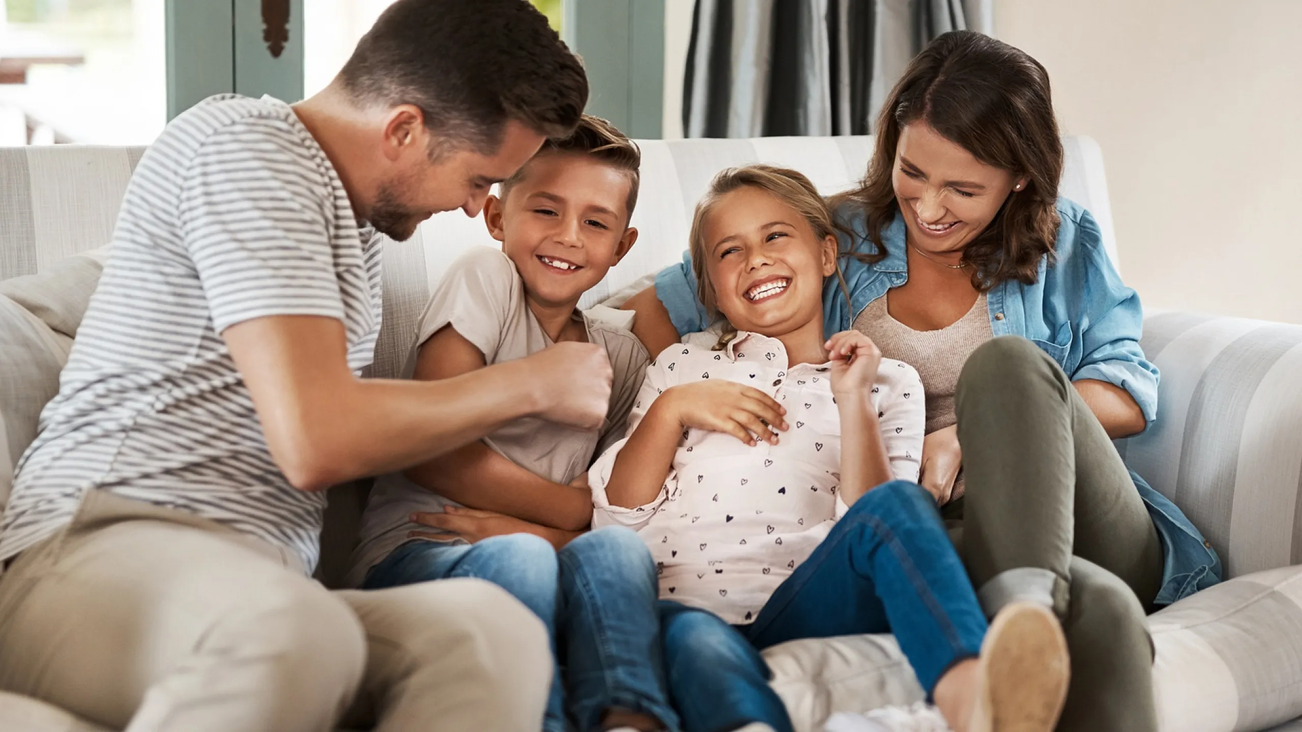 Happy family enjoying quality time together on a cozy living room couch, highlighting a welcoming and comfortable home environment.