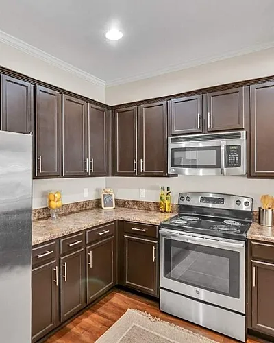 Modern kitchen with sleek stainless steel refrigerator, dark wood cabinets, and granite countertops, exuding elegance and functionality.