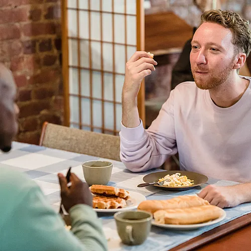 Cozy dining area with exposed brick wall and two people enjoying a delicious breakfast together.