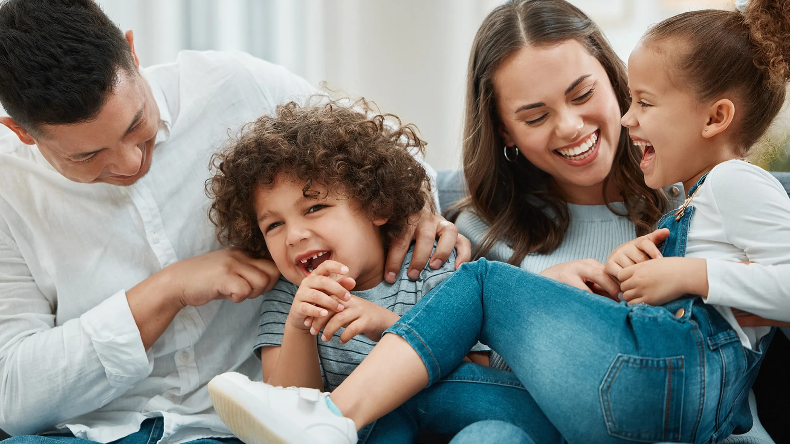 Happy family enjoying quality time laughing together on a cozy living room sofa, showcasing a warm and inviting home atmosphere.