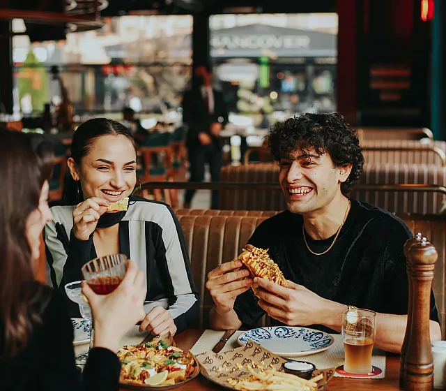 Joyful group enjoying delicious food at a cozy restaurant, creating a vibrant and inviting dining atmosphere.