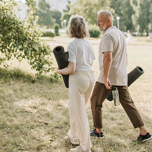 Peaceful park stroll with fitness mats, embraced by lush greenery and sunlight.