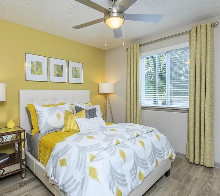 Inviting bedroom with vibrant yellow accents, elegant decor, and natural light through large windows.