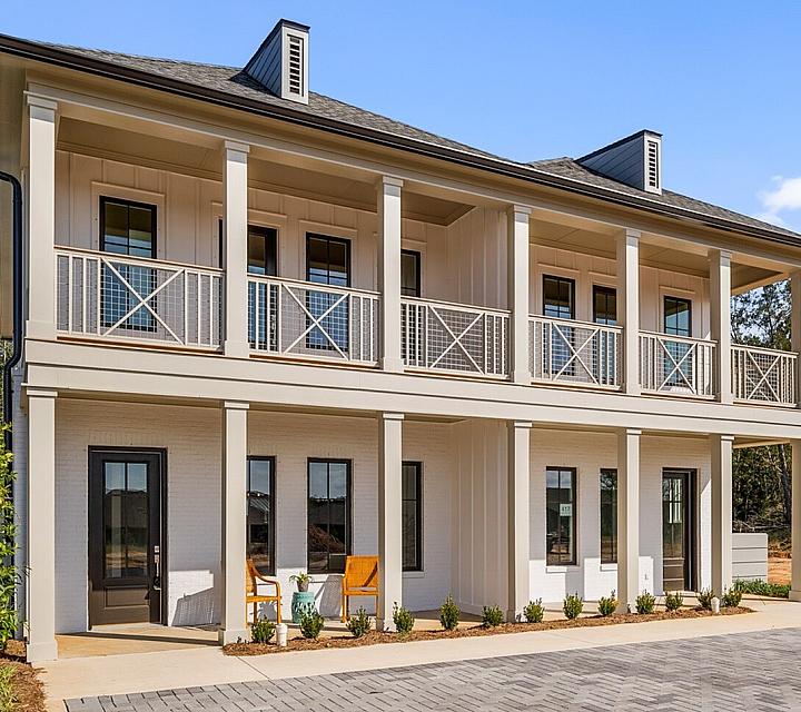 Elegant two-story villa with colonial-style balconies and serene outdoor seating in a picturesque setting.