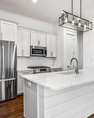 Elegant modern kitchen with sleek stainless steel appliances, white cabinetry, and a stylish island with pendant lighting.