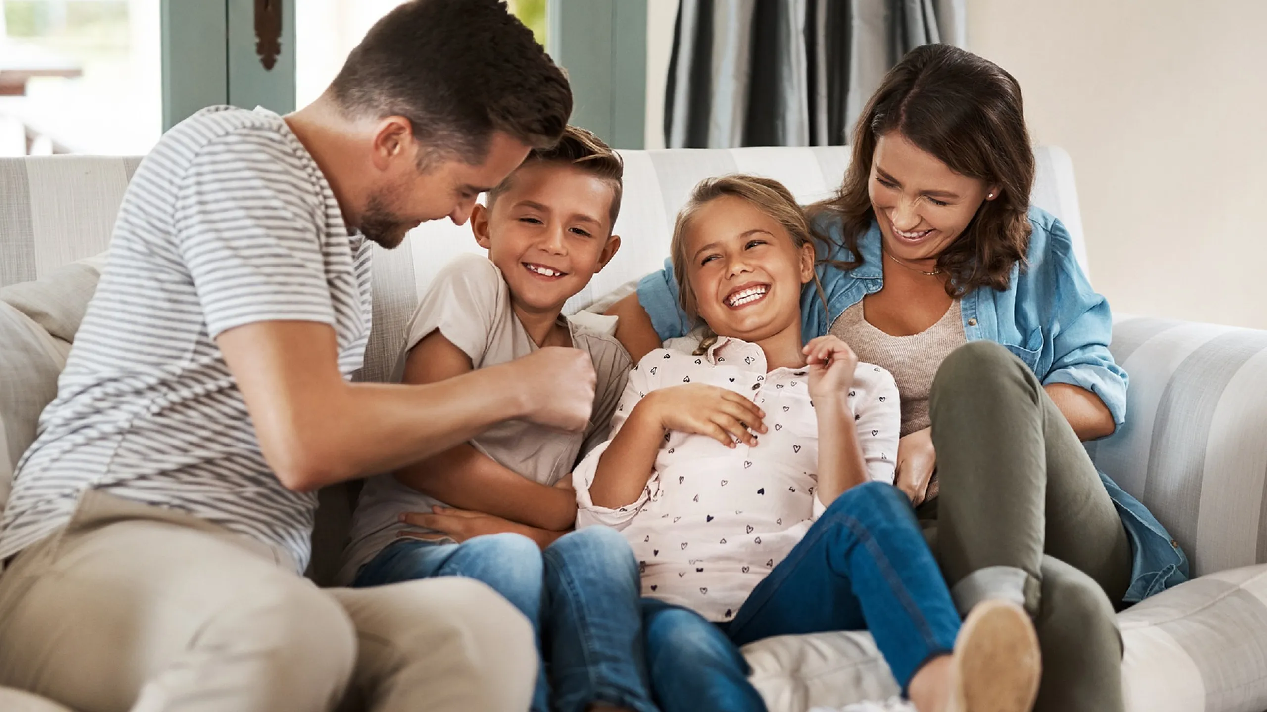 Joyful family enjoying quality time together on a cozy, sunlit sofa in a welcoming living room.