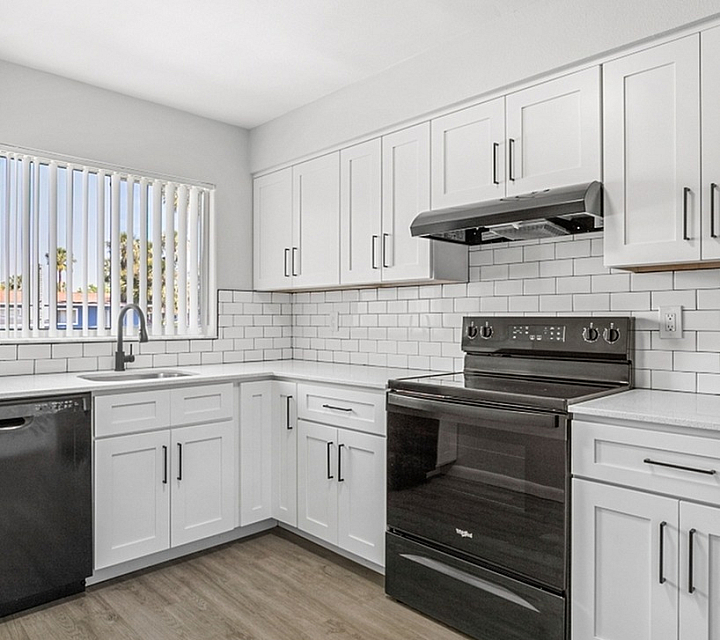 Modern kitchen with sleek black appliances, elegant white cabinetry, and stylish subway tile backsplash, offering a bright and inviting atmosphere.