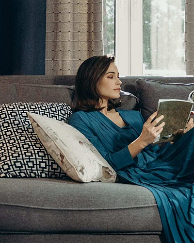 Cozy living room with elegant decor, featuring a plush gray sofa adorned with patterned cushions, a stylish armchair, and a classic ceramic lamp for a relaxing ambiance.