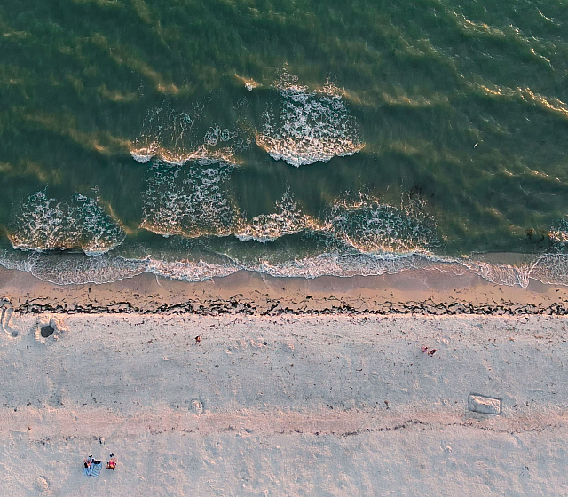 Breathtaking aerial view of a serene beach with gentle waves crashing on the sandy shore, perfect for relaxation and tranquility.