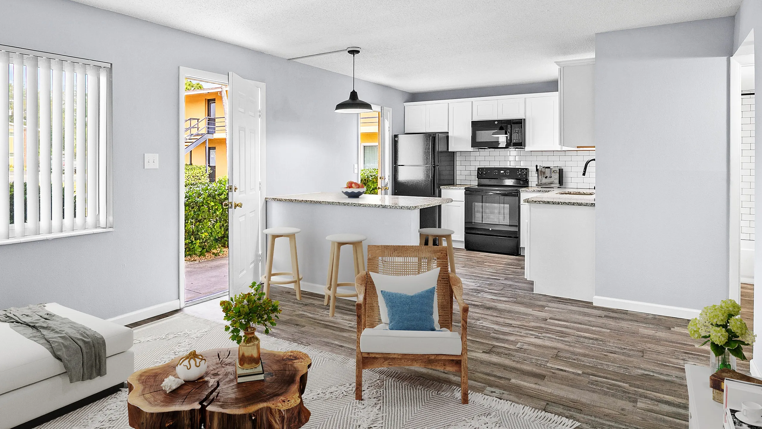 Bright open-plan living space featuring stylish kitchen with modern appliances and cozy seating area leading to outdoor view.