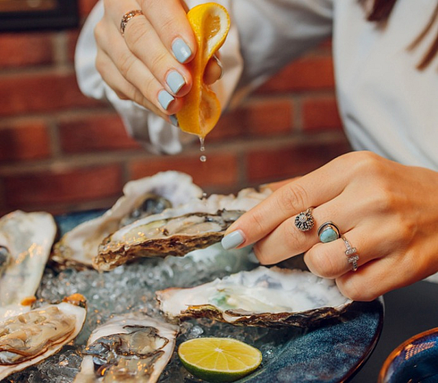 Gourmet dining experience with fresh oysters, elegantly garnished with lemon on a bed of ice, perfect for seafood lovers.