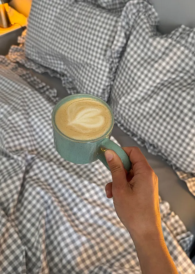 Inviting bedroom setting with cozy checkered bedding, ambient lighting, and a warm cup of coffee, creating the perfect relaxation space.