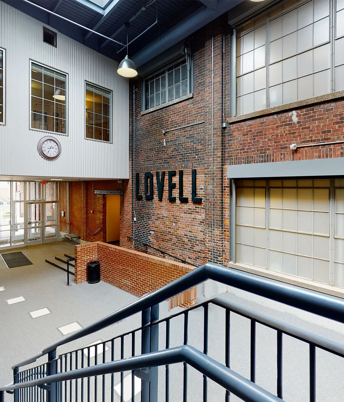Inviting industrial-style apartment entrance with exposed brick walls, large windows, and contemporary design elements.