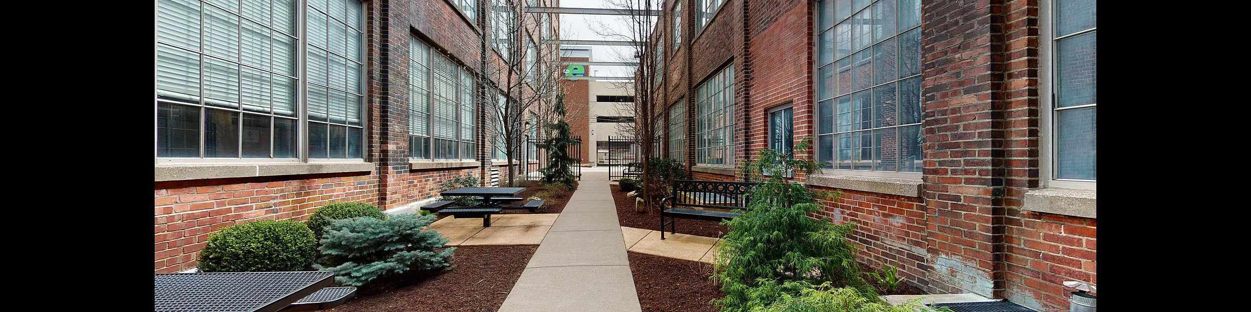 Charming urban courtyard with lush greenery, brick walls, and cozy seating areas, offering a serene escape in a city setting.