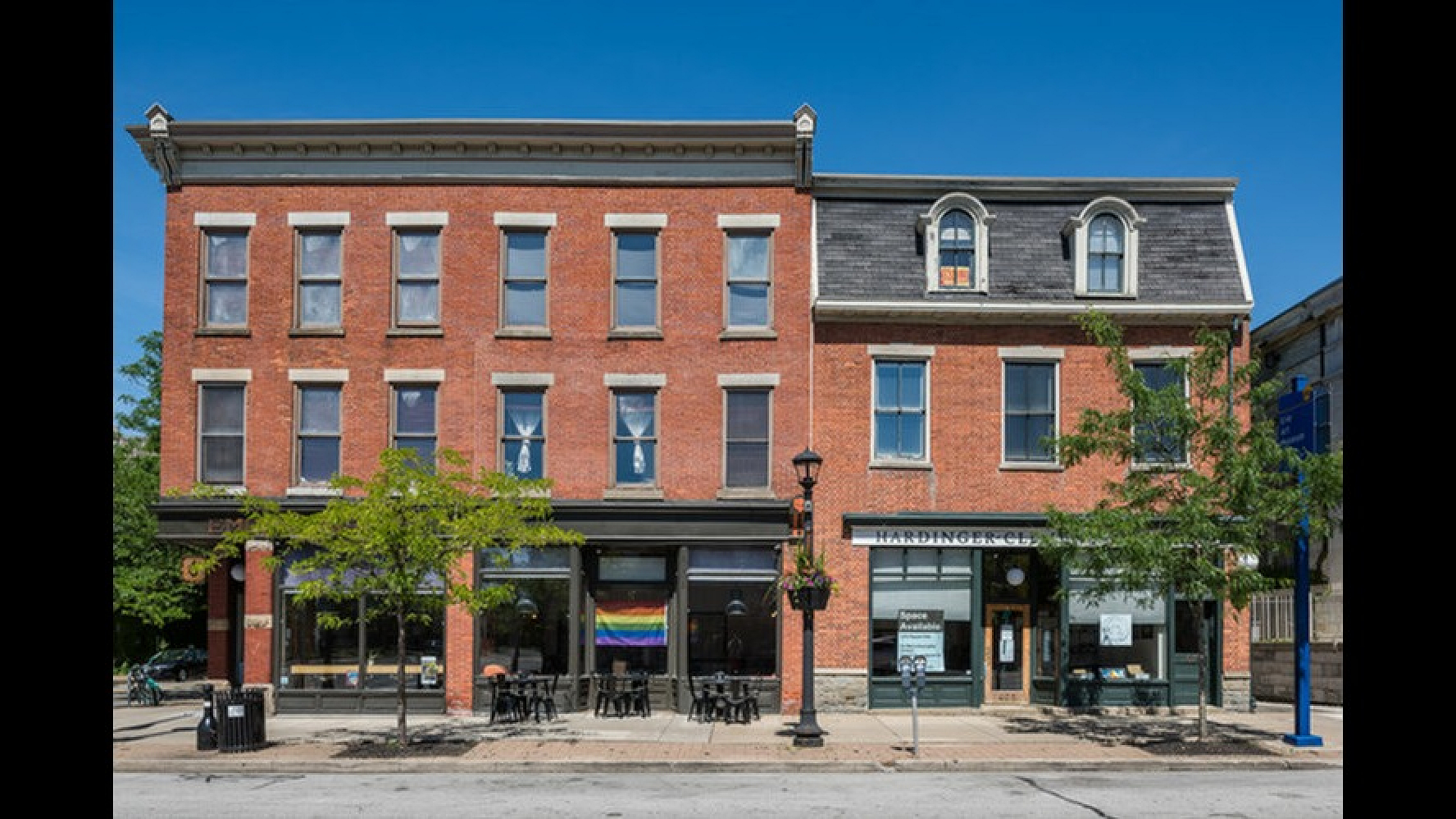 Charming brick building with vibrant street-level cafes and storefronts, featuring classic architectural details and inviting atmosphere.