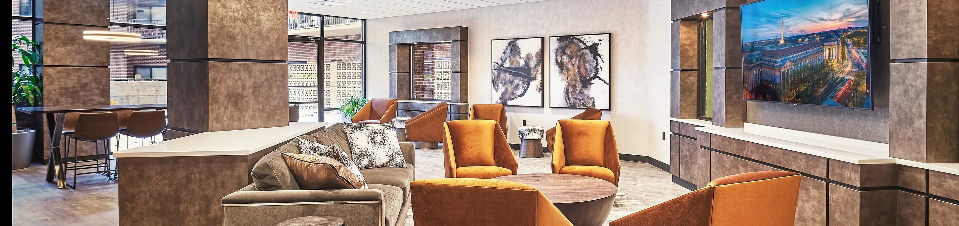 Modern lobby with chic orange chairs and stylish decor, featuring a spacious seating area and contemporary lighting.