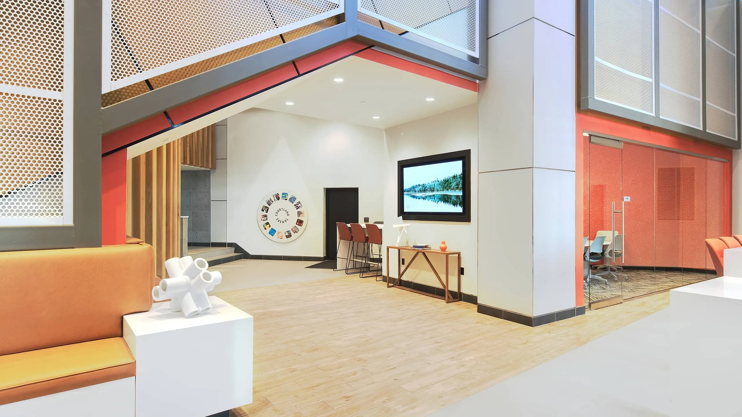 Modern apartment lobby with sleek design, featuring vibrant orange seating, stylish decor, and a contemporary open layout.