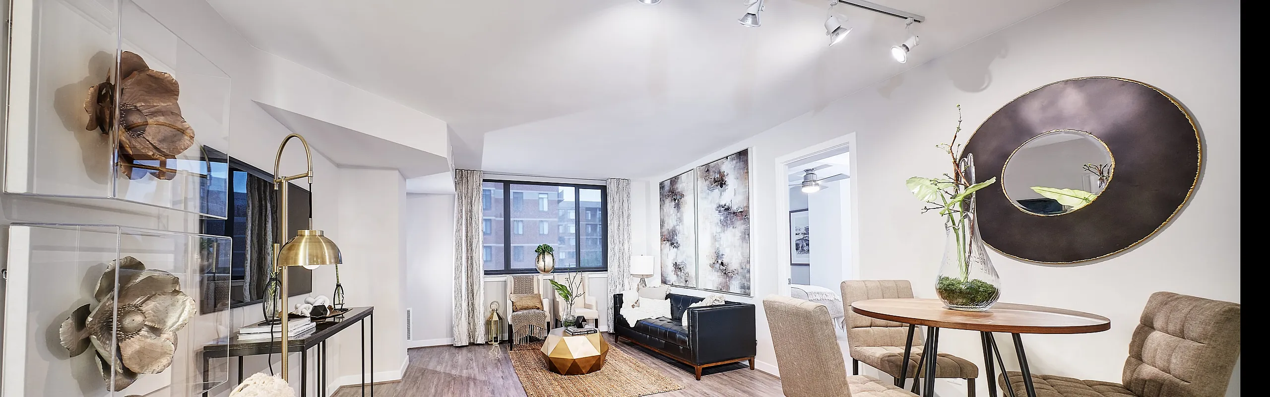 Modern open-concept living room and dining area with stylish furnishings, accent lighting, and large windows offering natural light.