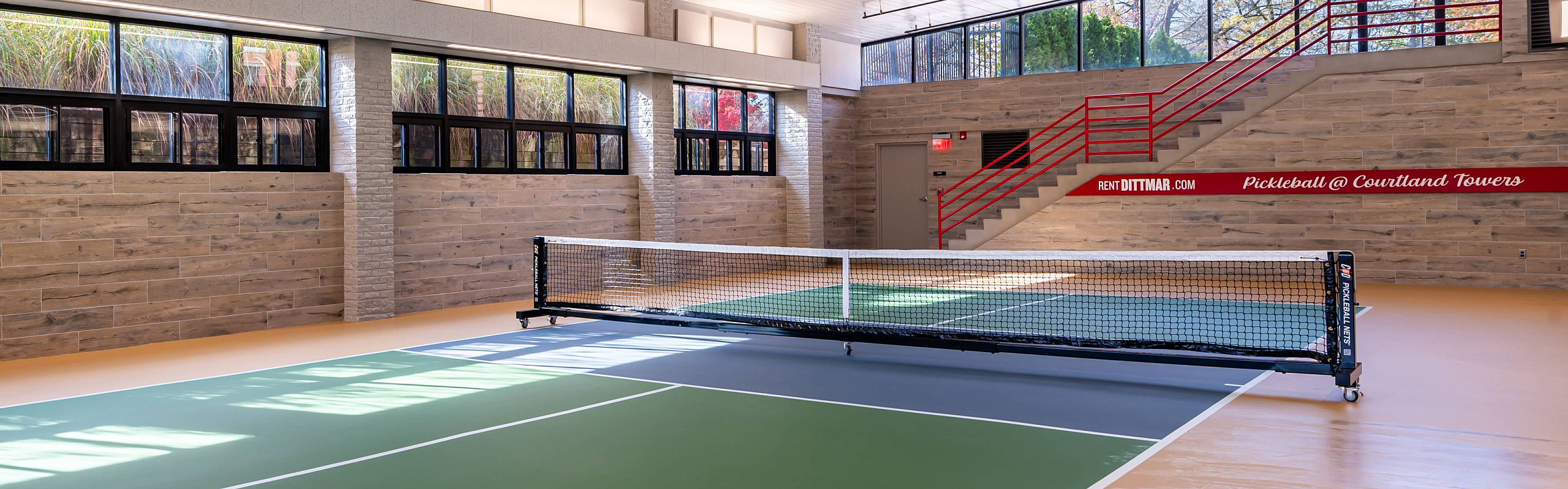 Bright indoor pickleball court with natural light and modern design at Courtland Towers.