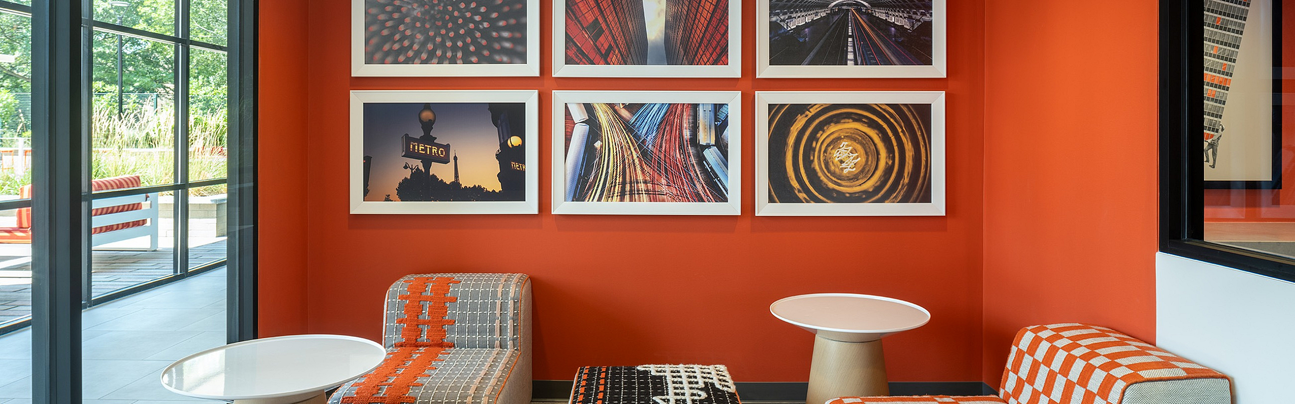 Vibrant lounge area featuring modern seating, bright orange accent wall, and dynamic artwork, creating an inviting atmosphere.