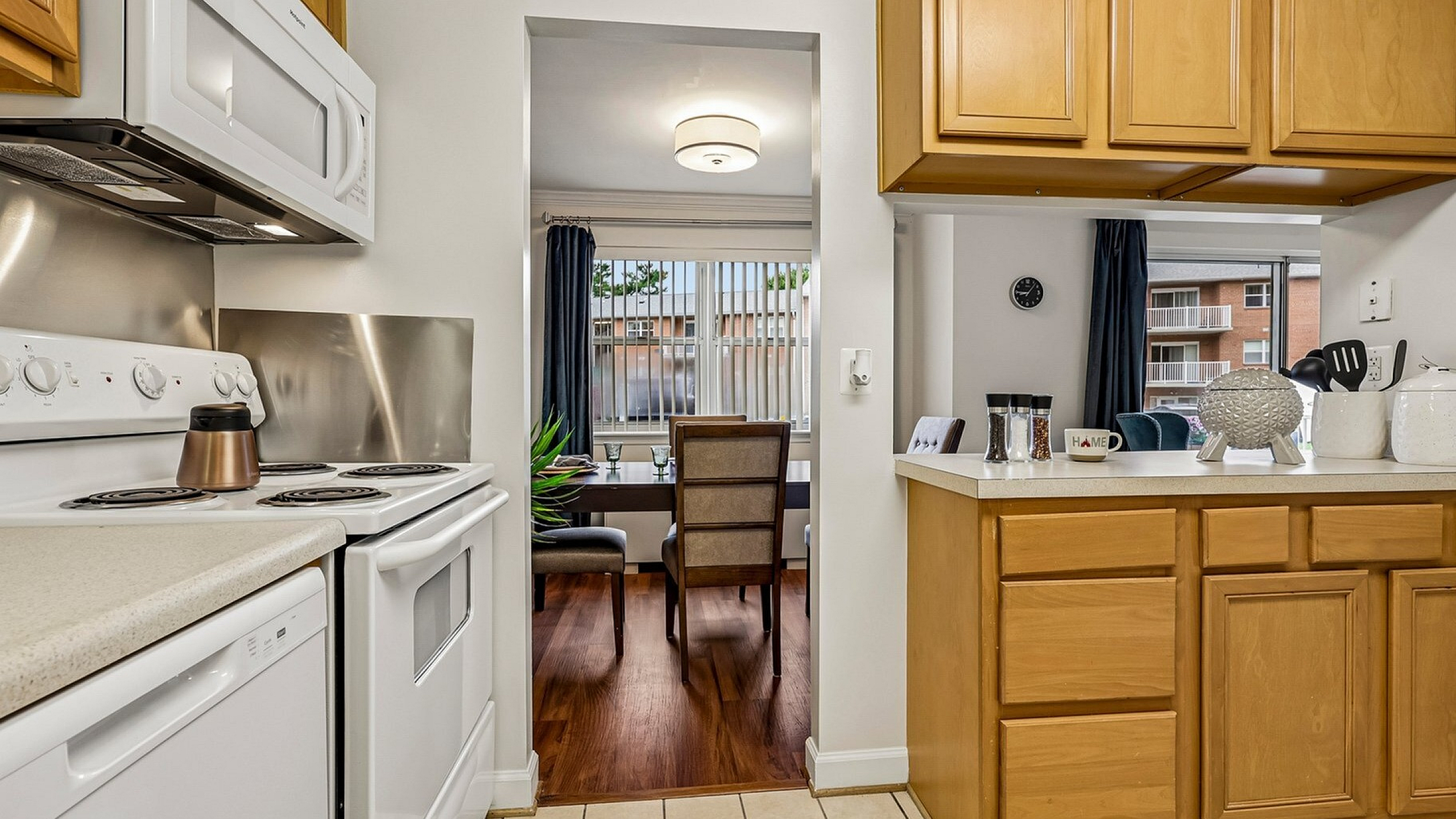 Inviting kitchen with wooden cabinetry, modern appliances, and a view into a bright dining area with elegant seating.