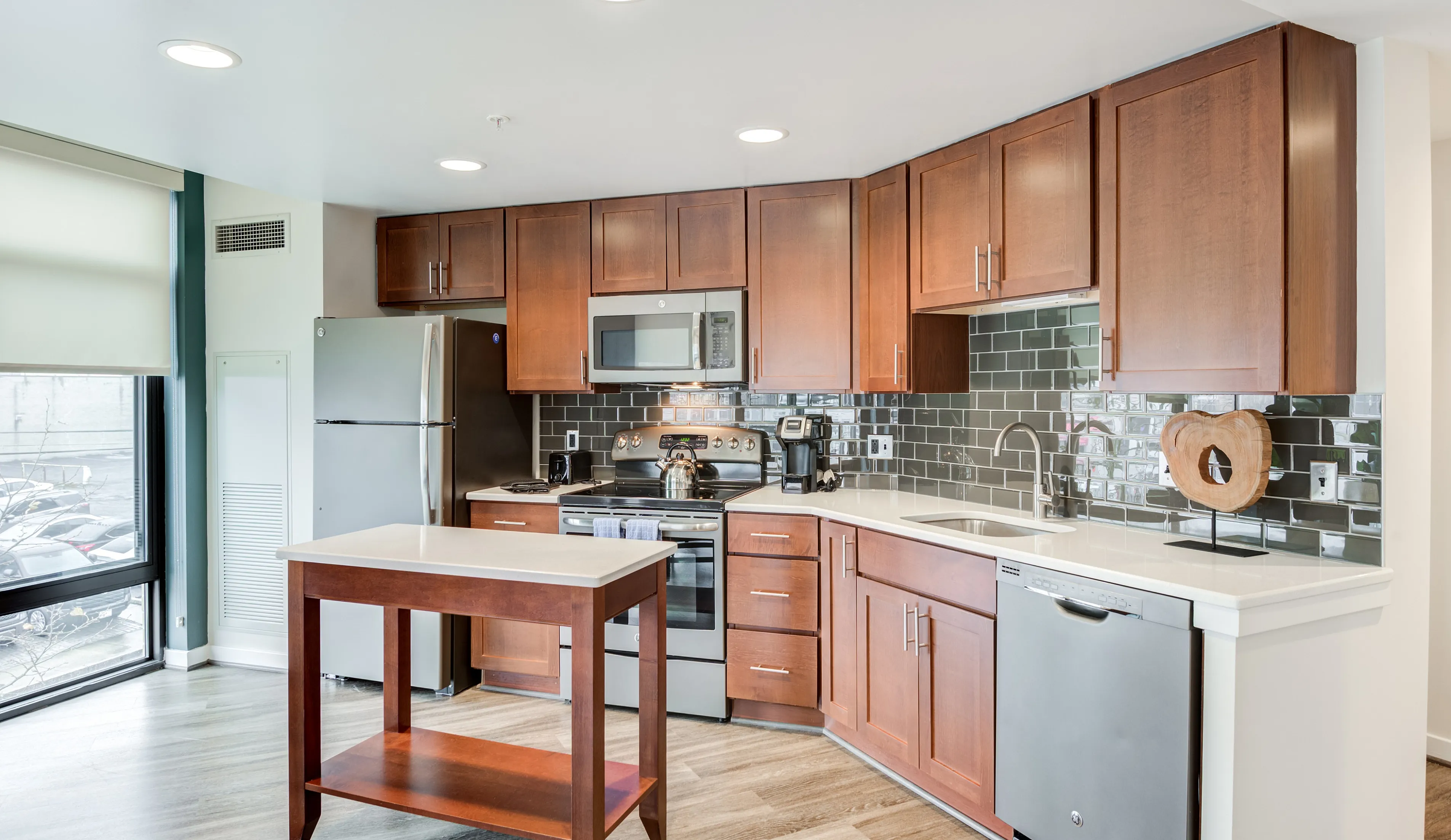 Modern kitchen with elegant dark wood cabinets, sleek countertops, and stainless steel appliances under soft daylight.