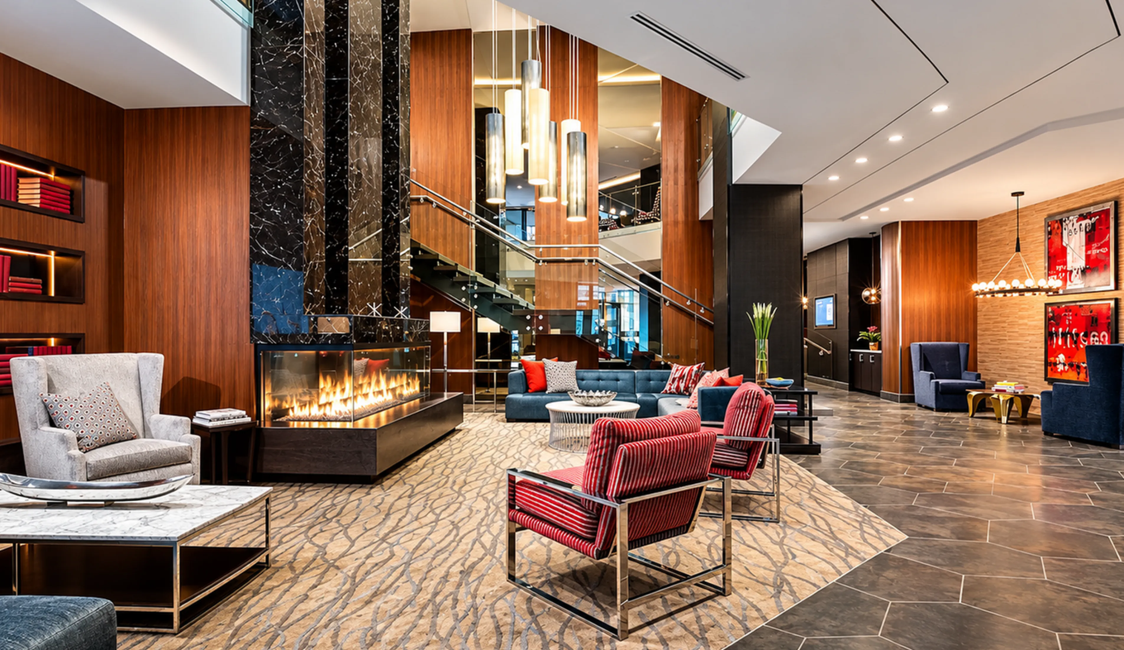Luxurious apartment lobby featuring modern decor, elegant marble fireplace, stylish seating areas, and ambient lighting for a welcoming atmosphere.