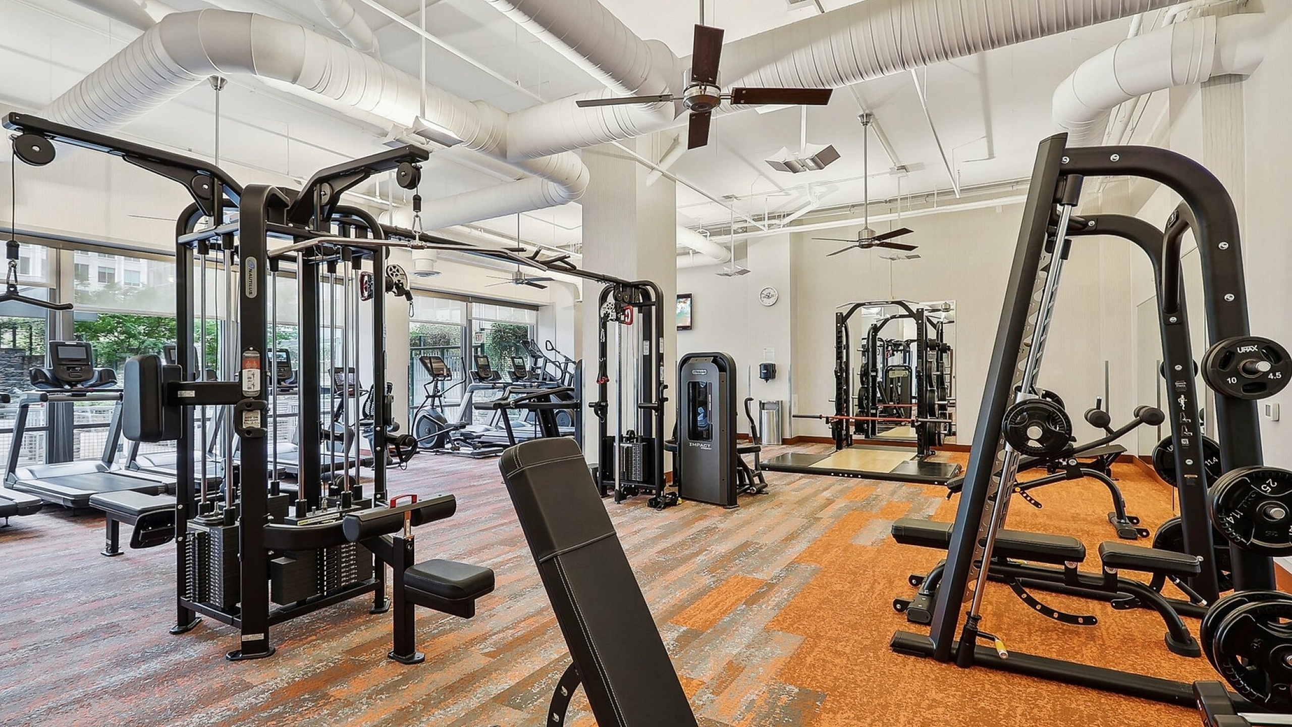 State-of-the-art fitness center with modern equipment, bright lighting, and floor-to-ceiling windows for a contemporary workout experience.