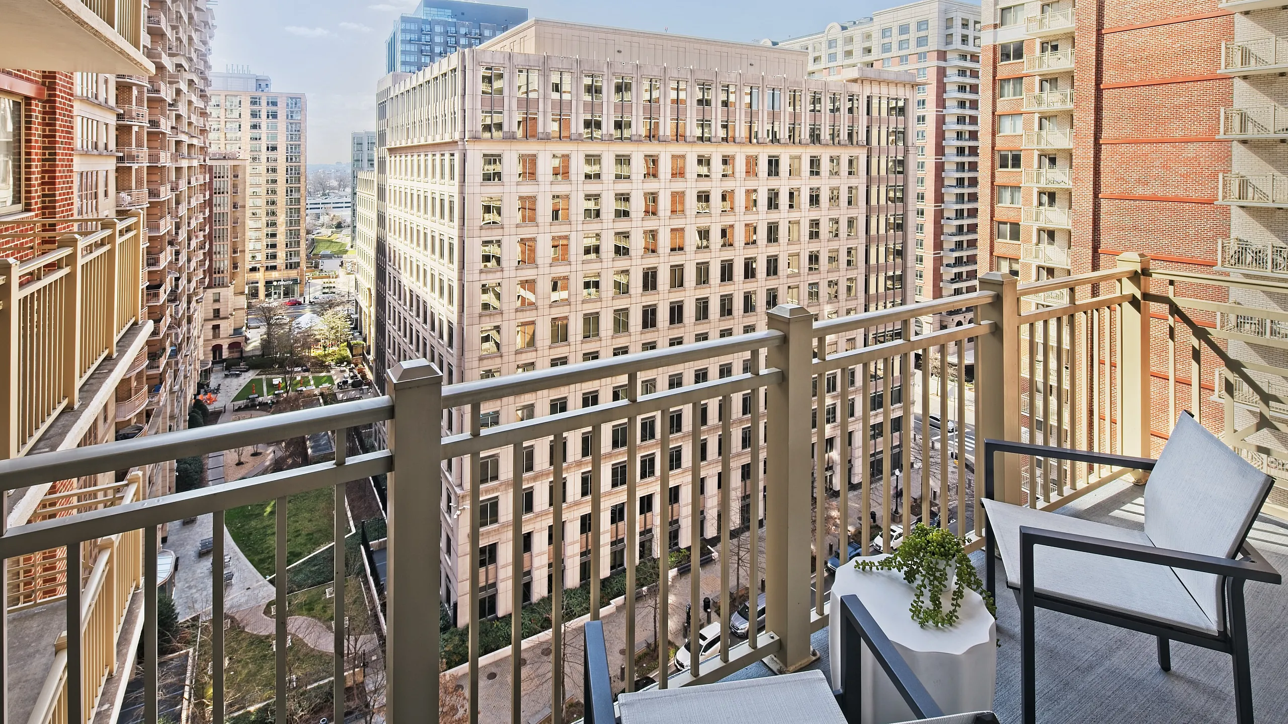 Elegant balcony view featuring modern outdoor seating overlooking a vibrant urban cityscape with towering buildings and lush green spaces.