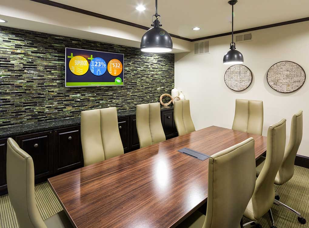 Interior of conference room at AMLI Campion Trail apartment building with wood table and eight chairs and big screen TV