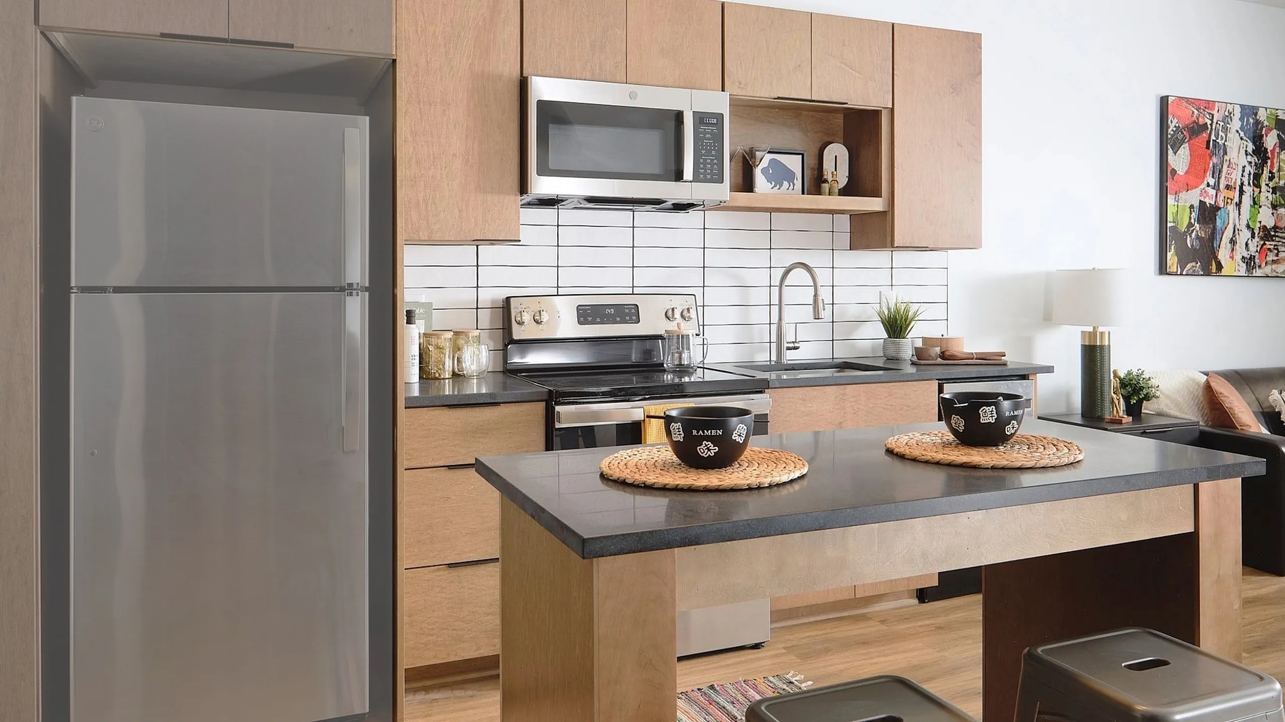 Modern kitchen in a Rails apartment with dark countertops, wooden cabinets, and a central island bench. The space has a chic, contemporary design.