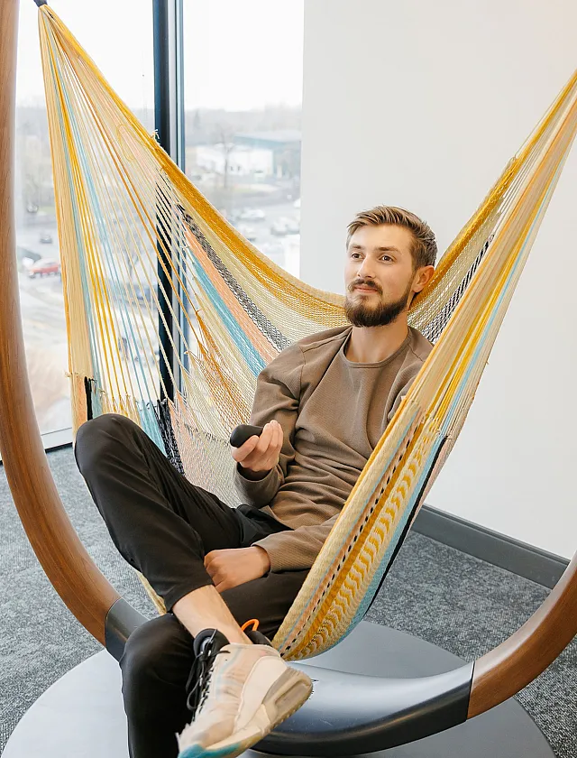 Modern apartment living space with a stylish hammock chair and expansive window views, perfect for relaxation.