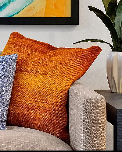 Chic living room corner featuring a cozy gray sofa with vibrant blue and orange cushions, alongside a modern side table with stylish plant decor.