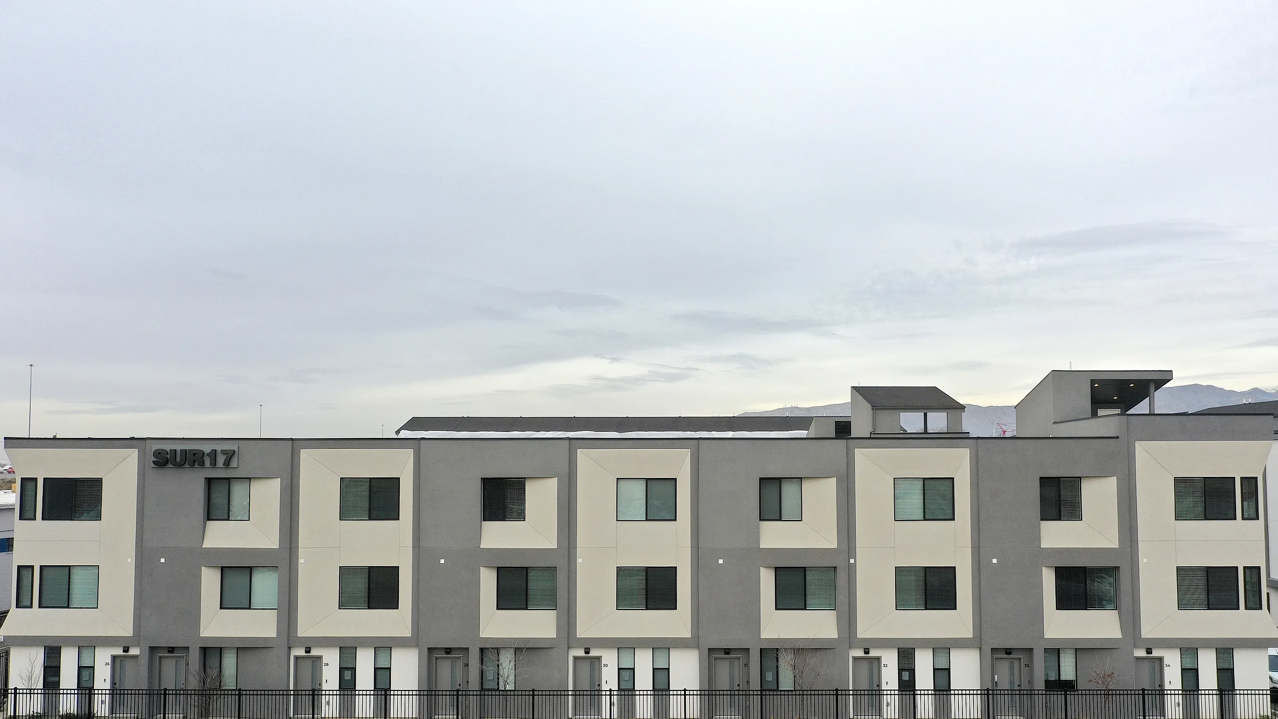 Modern apartment complex with sleek design and large windows, offering mountain views and contemporary living.