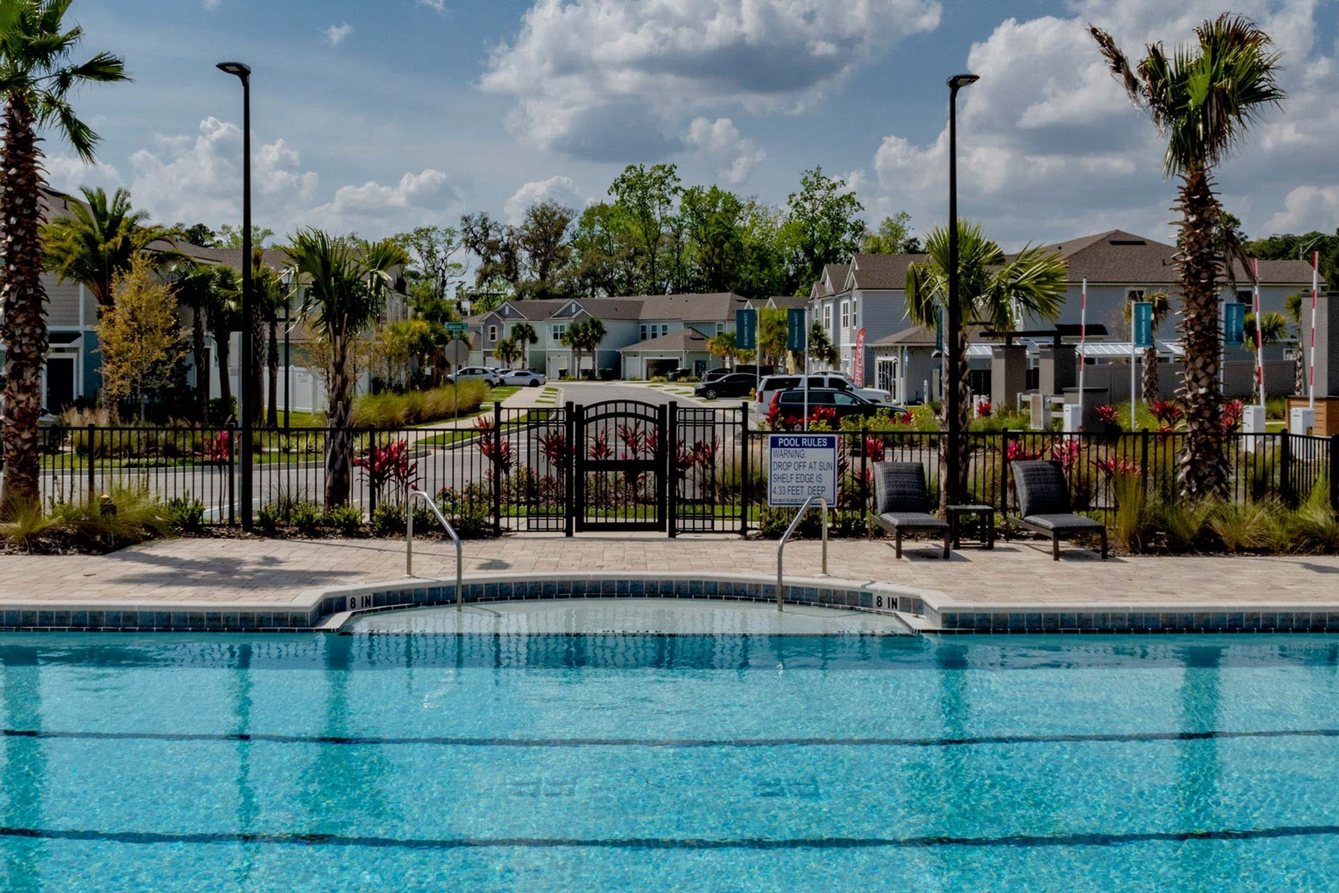 Outdoor pool with community in the background in the daytime