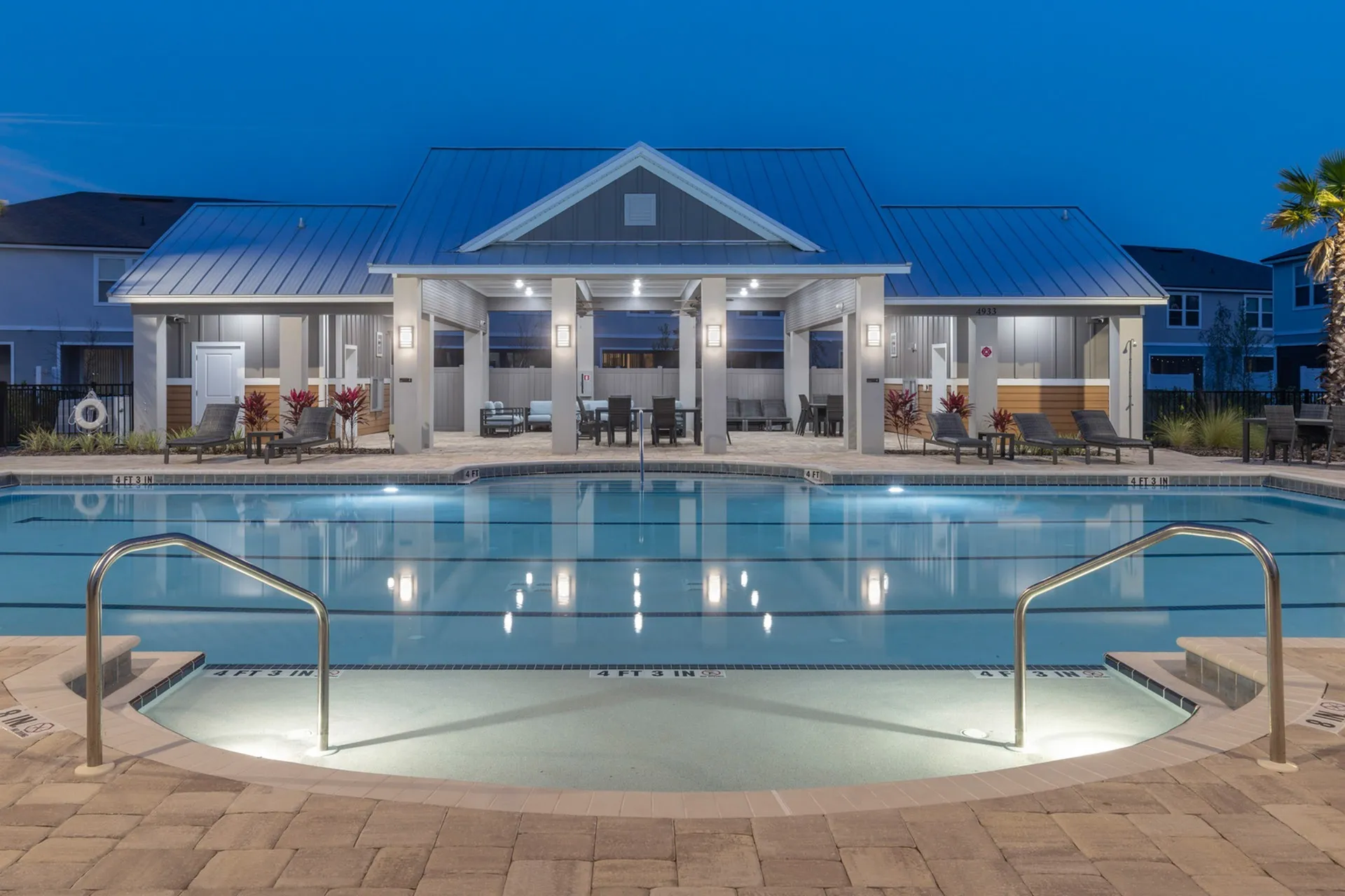 Outdoor pool with community in the background at dusk