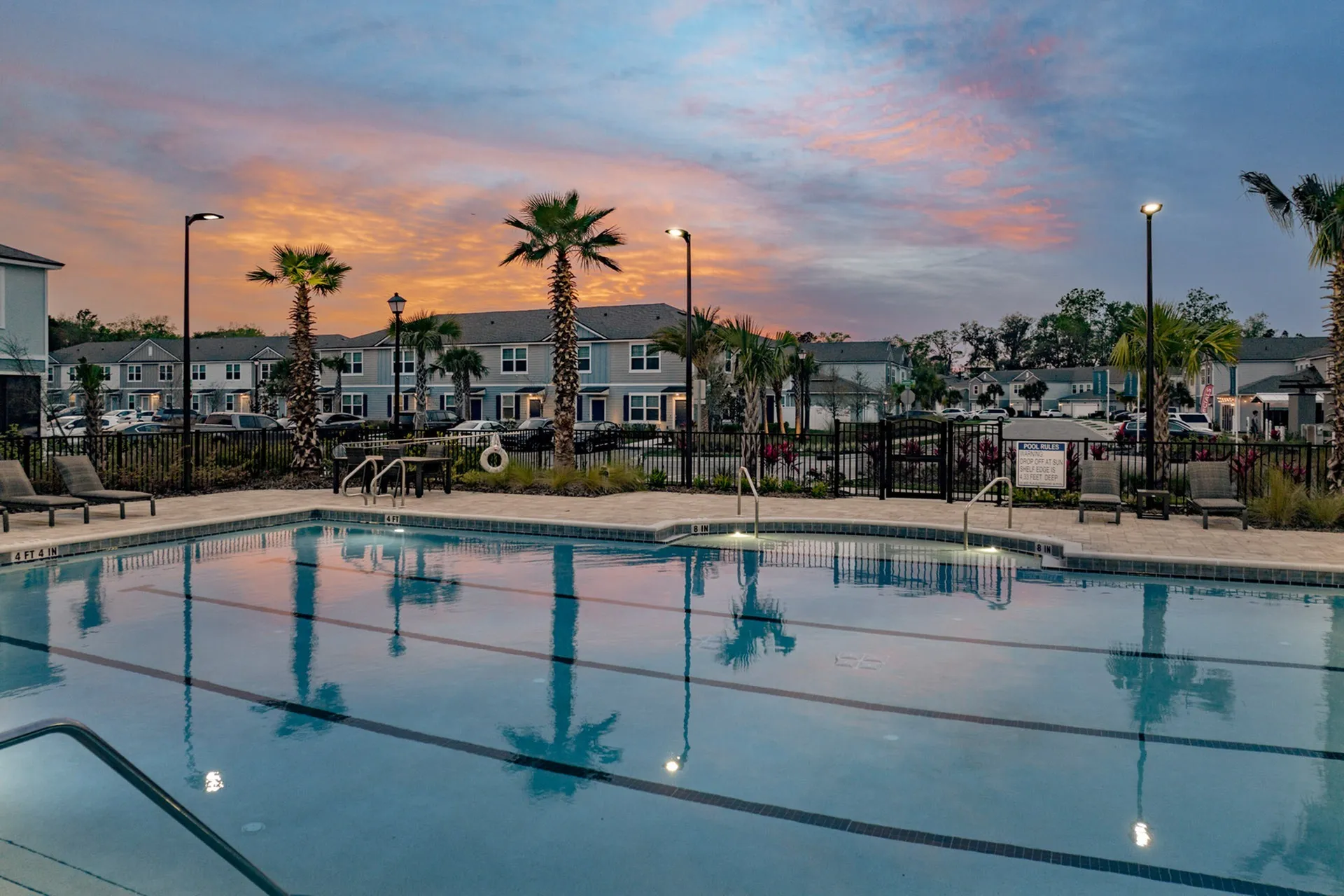 Outdoor pool with community in the background at dusk
