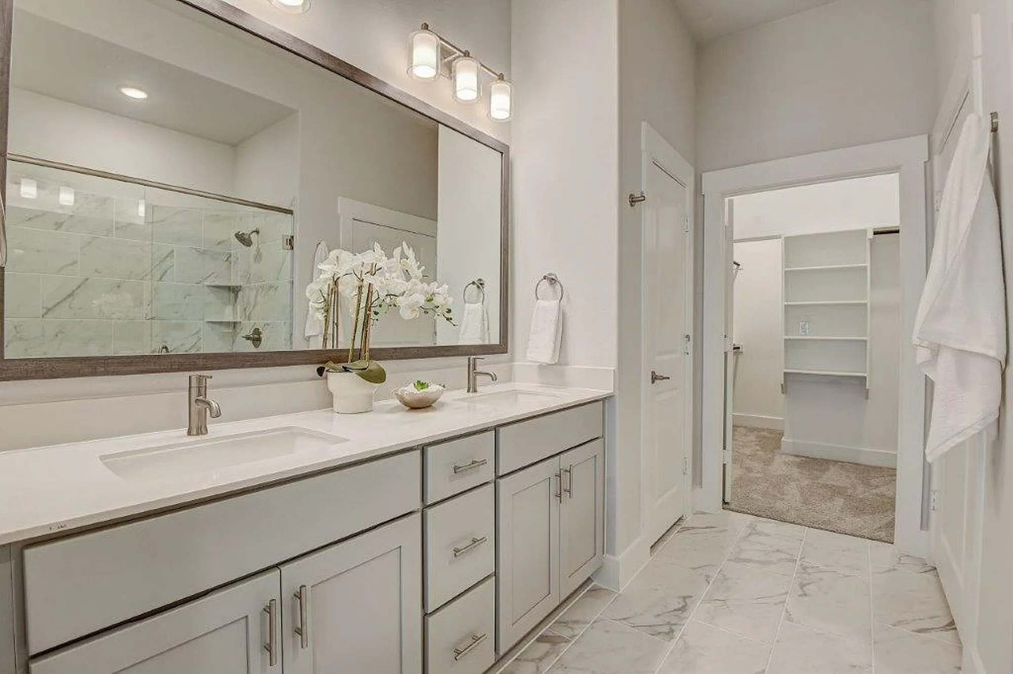 Bathroom with double vanity and large mirror with view of the closet