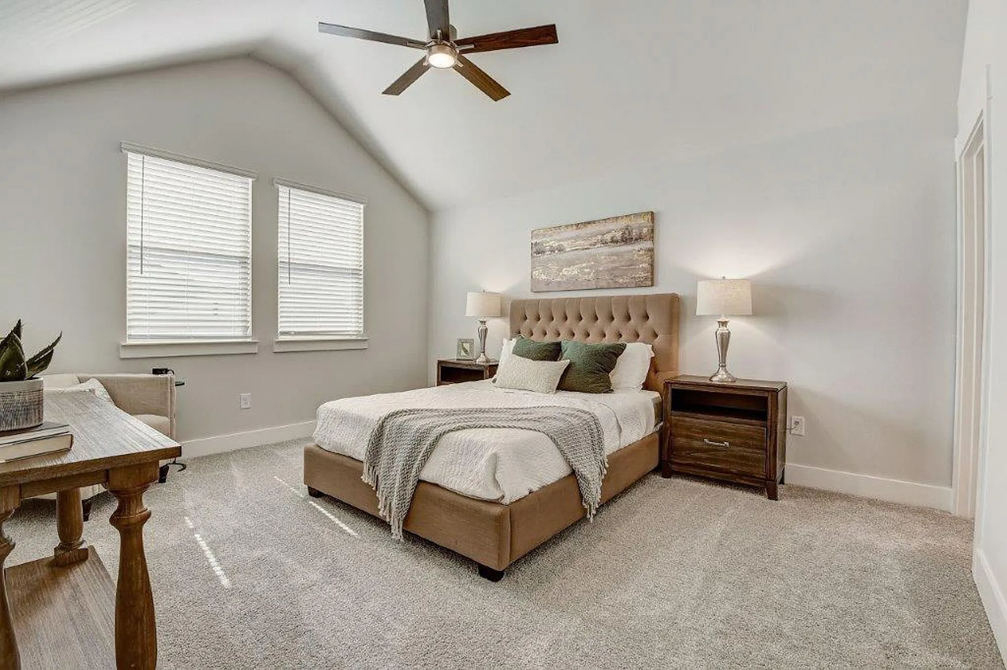 Furnished Main bedroom with lighted ceiling fan, bed, windows and bed-side tables