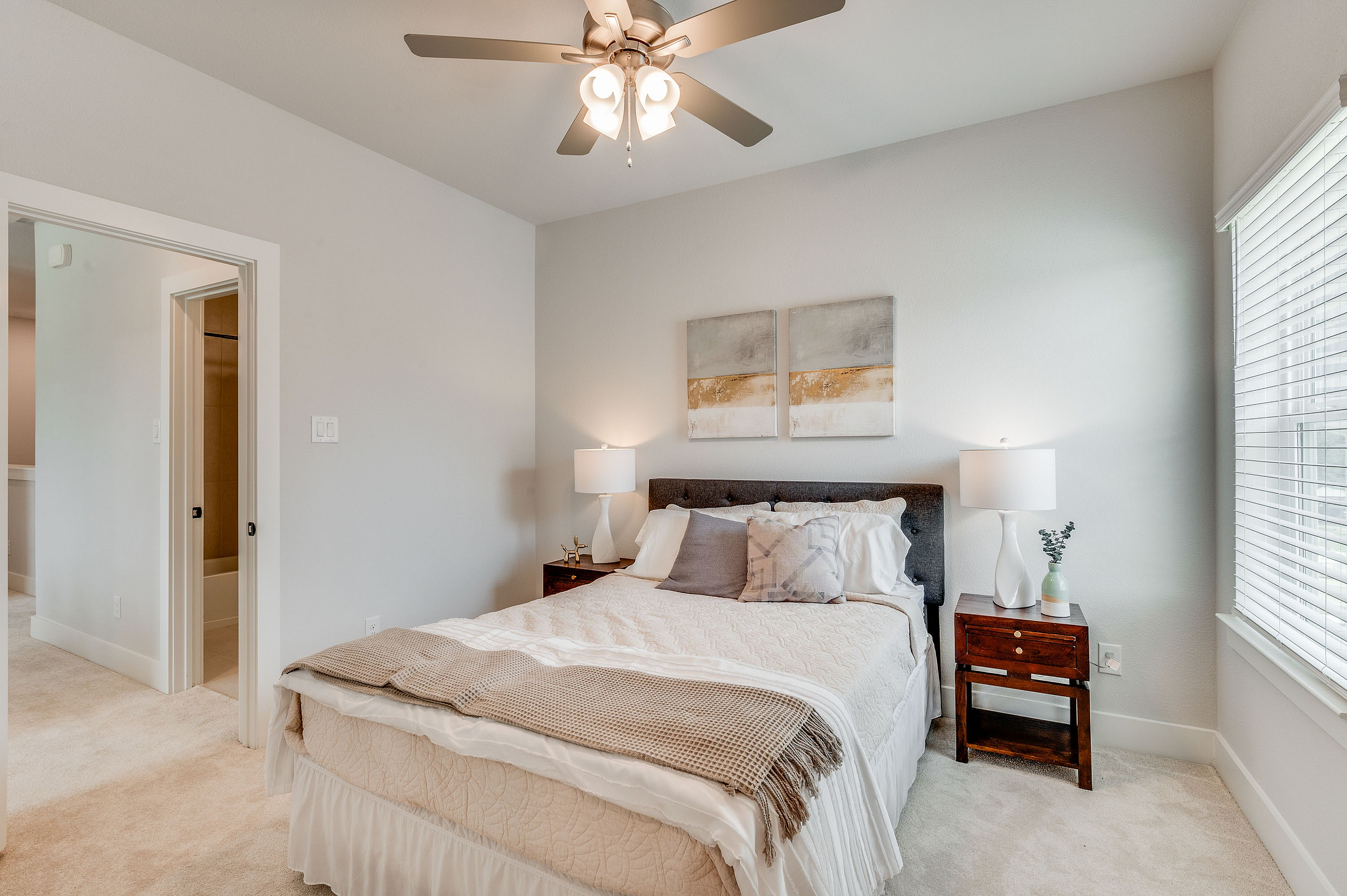 Furnished guest bedroom with ceiling fan and carpet